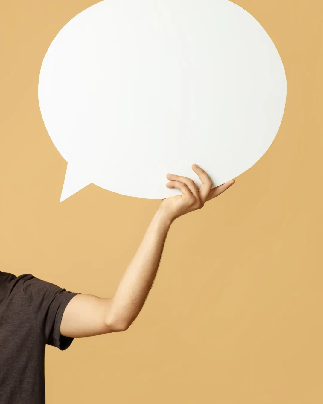 Main qui tient une grande bulle de dialogue blanche et vide sur fond orangé