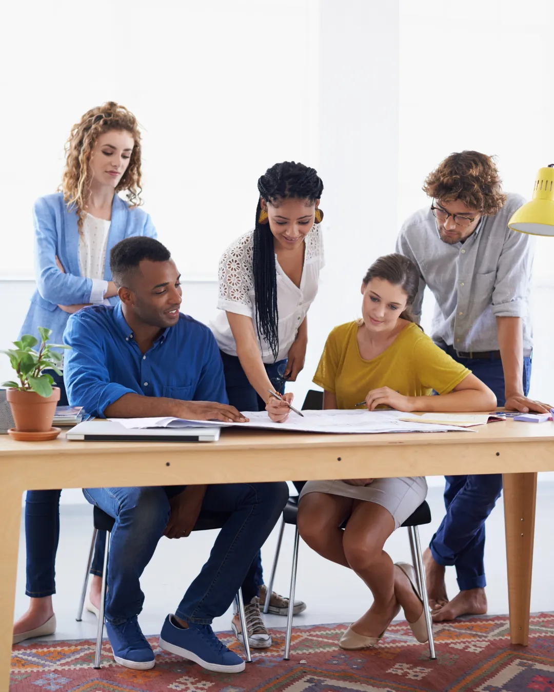 Groupe de personnes penchées sur des documents autour d'une table de travail