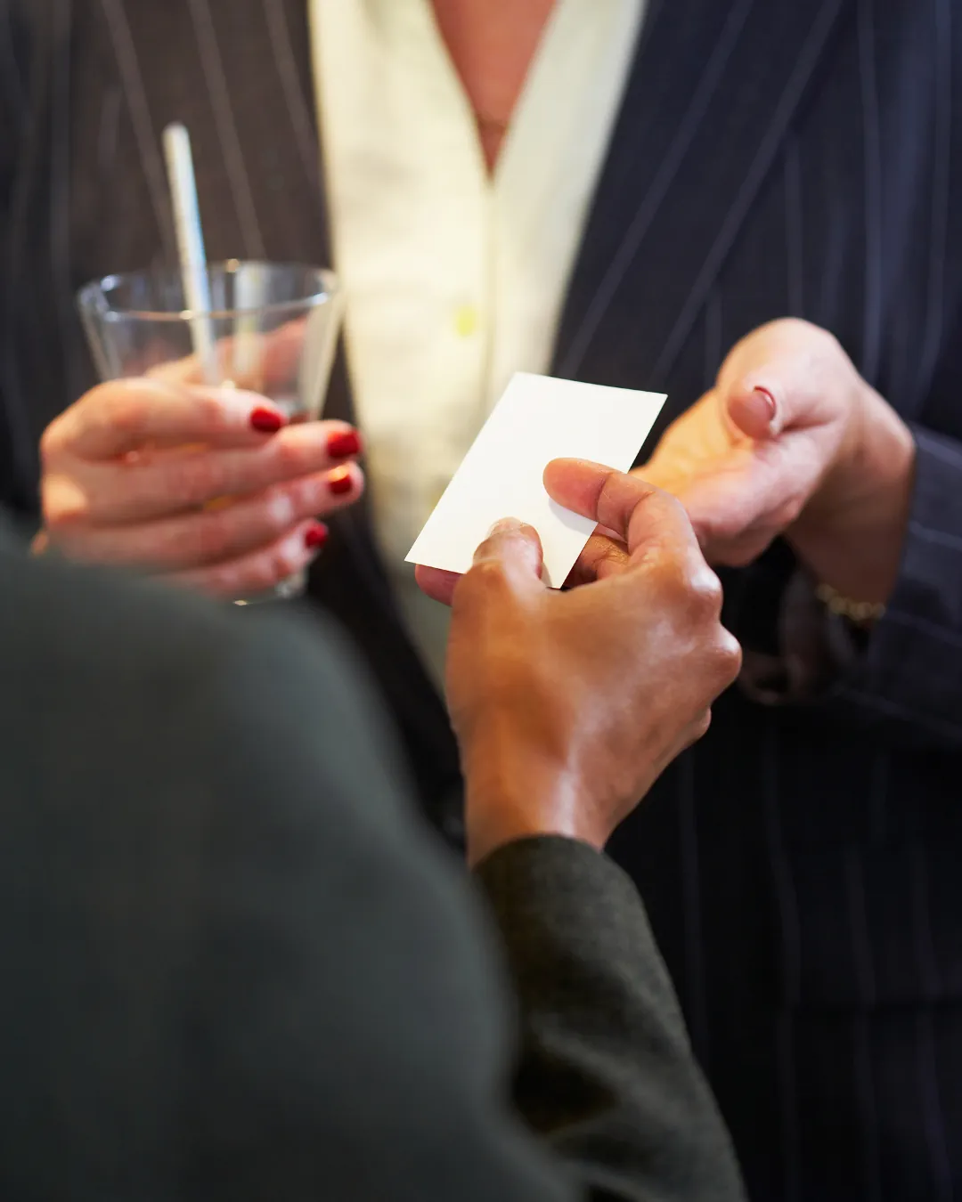 Deux personnes échangent une carte de visite, un verre à la main