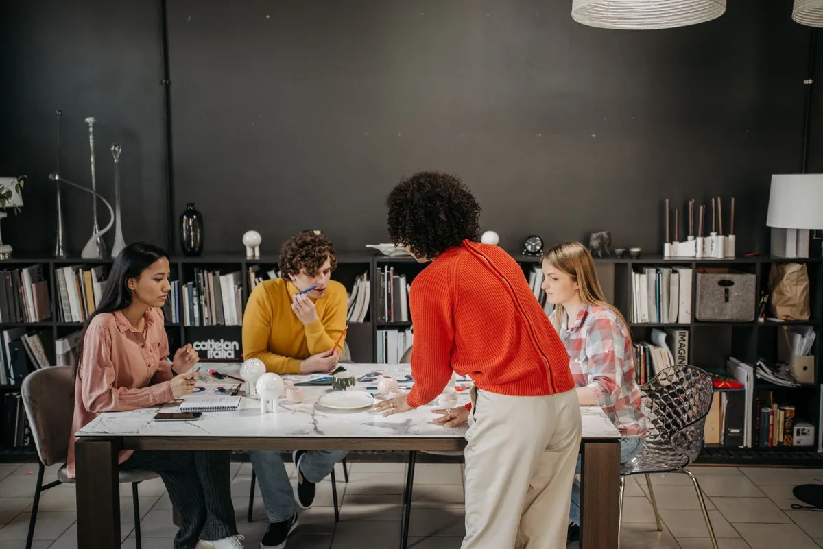Quatre jeunes professionnels travaillent ensemble autour d'une grande table, dans un espace de travail partagé